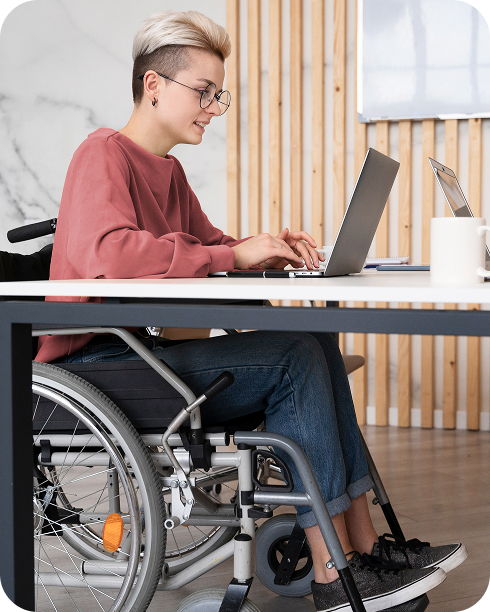 Joven en silla de ruedas usando gafas trabajando en una laptop en un espacio moderno