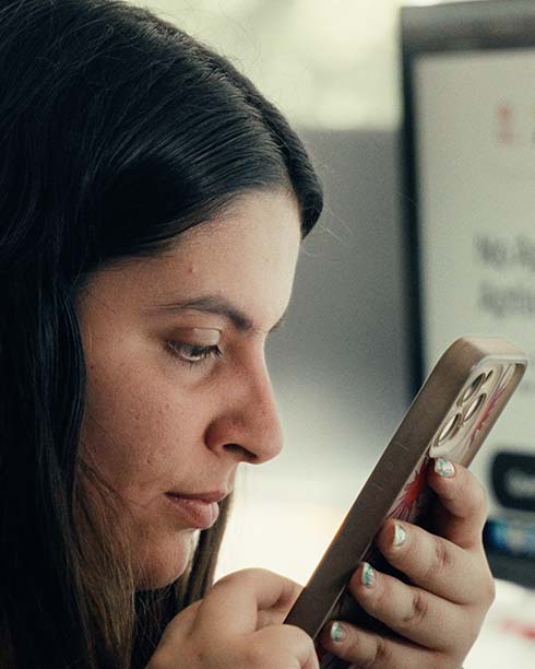 Mujer sonriente usando gafas mirando un teléfono durante una videollamada